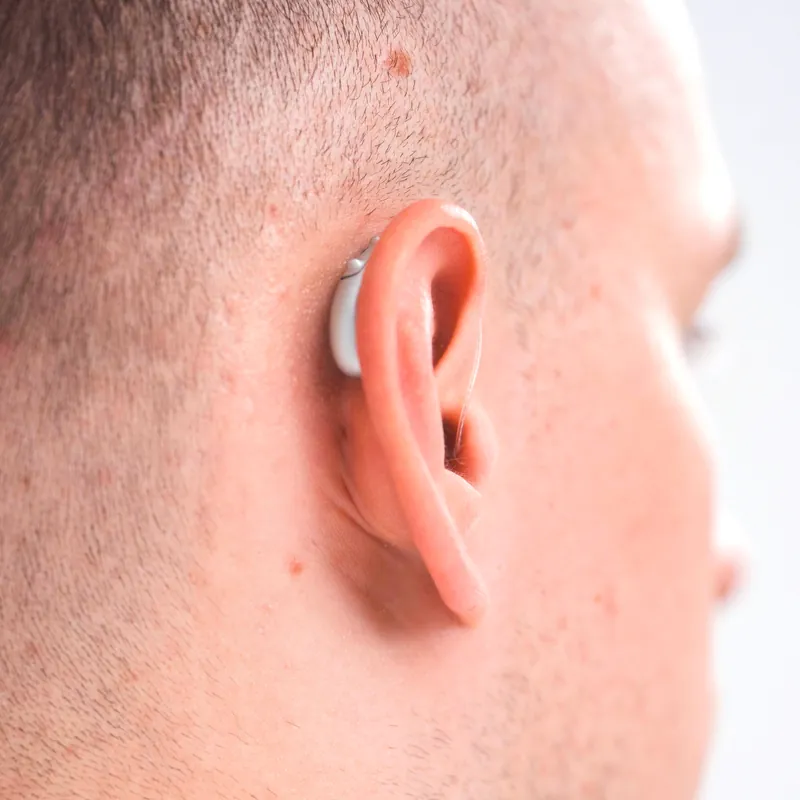 Užausinis klausos aparatas ant paciento ausies
